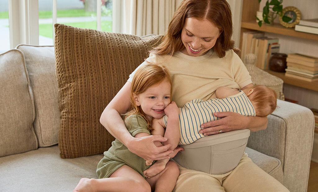 Mama die haar baby borstvoeding geeft met de heupzitje