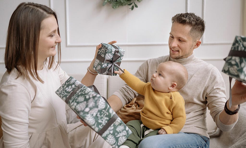 Baby met ouders na slaap cadeautjes uitpakken.