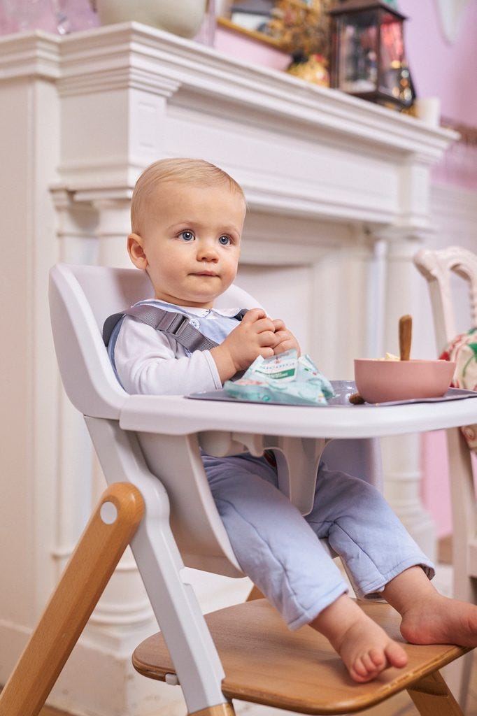 Baby zitten in kinderstoel, aan tafel vastevoeding eten.<br />
