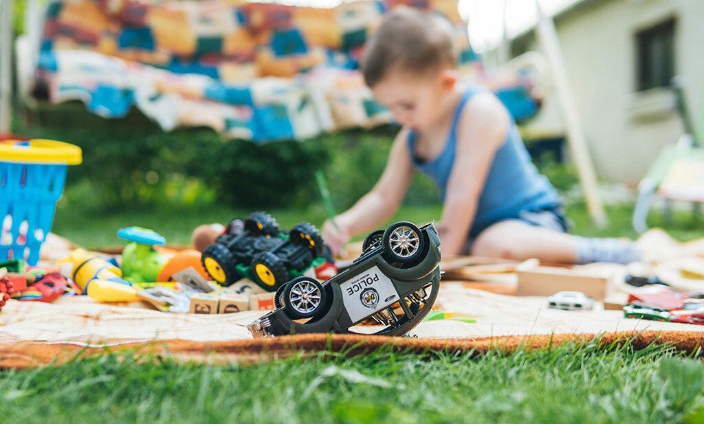 kind speelt thuis in de tuin met speelgoed in de zomer