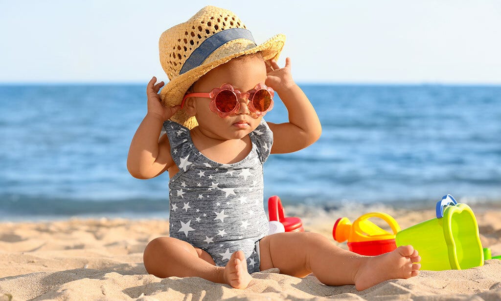 baby op het strand met hoed en zonnebril